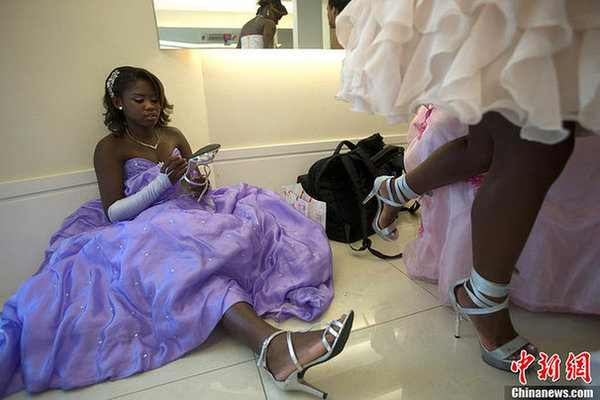 当地时间2012年11月8日,巴西里约热内卢,一名即将年满15岁的女孩坐在地上,调整高跟鞋,准备参加人生的首次社交舞会。(图片来源:中新网)