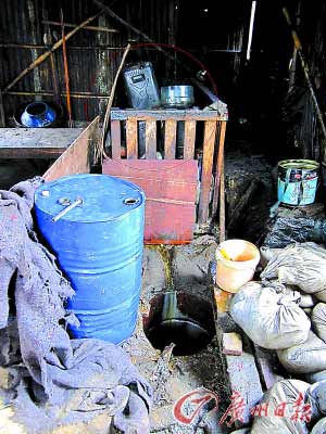 熬好的油经过过滤(图中红圈所示),流到地下的桶里,然后被装入旁边的蓝色大桶,运往批发市场。