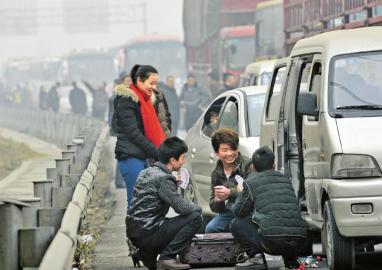 找乐 1月27日,成自泸高速大雾封闭,高速路上玩耍扑克的旅客。