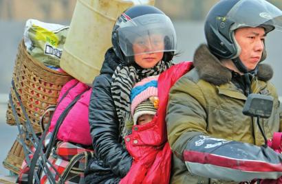 依偎 一家三口骑摩托车返乡。