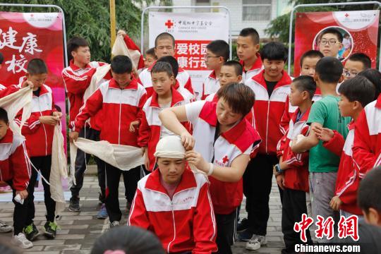 6月11日至13日，中国红十字基金会在甘肃省援建的首批11个“博爱校医室”落成。图为在中国红基会、庆阳市西峰区红十字会救护师资指导下，显胜实验学校学生进行创伤包扎的实操技能演练。　付春来 摄